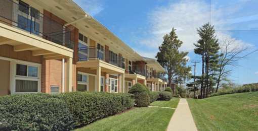 A long building with balconies and a green lawn in front.