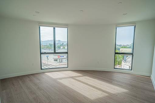 A large empty room with wooden floors and two windows.
