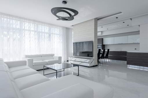 A modern living room with white furniture and a large window.
