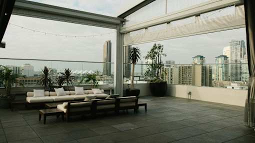 A rooftop patio with a couch, chairs, and a view of the city.