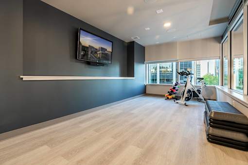 A room with a television on the wall and a row of exercise equipment.