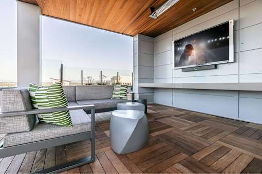 A modern living room with a grey sofa and a television on the wall.
