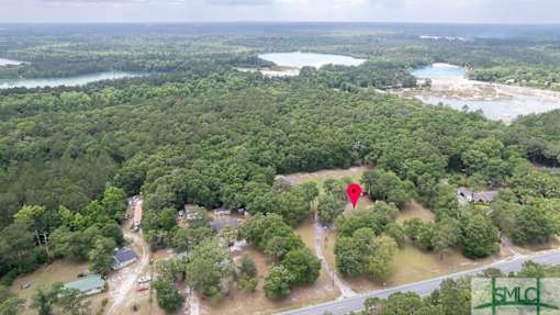 An aerial view of a lush green forest with a red pin marking a specific location.