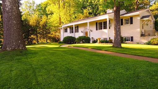A white house with a green lawn in front of it.