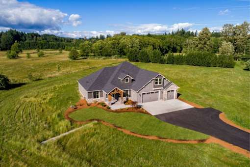 A house with a grey roof and a driveway in front of it.