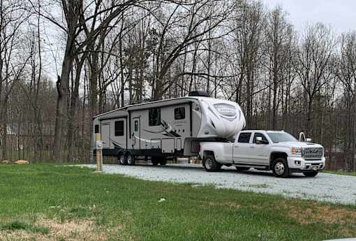 A white RV is being towed by a white pickup truck.