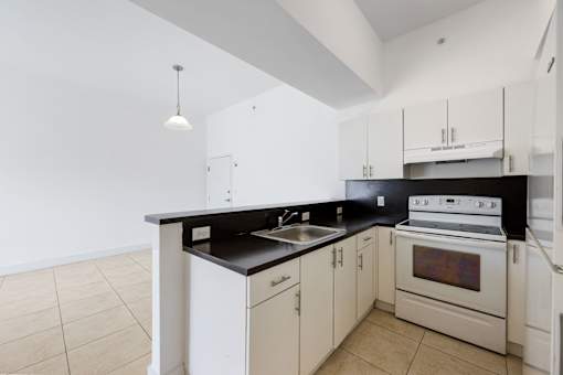 A kitchen with white cabinets and a black countertop.