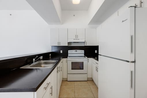 A kitchen with white cabinets and black countertops.