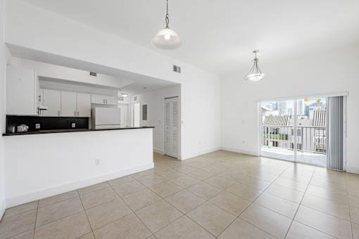 A spacious kitchen with a bar area and a large open floor plan leading to a balcony.