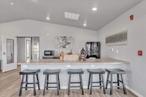 A kitchen with a bar area featuring four stools.