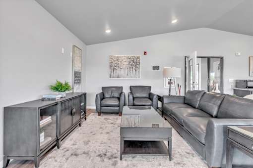 A grey living room with a grey couch, grey armchairs, and a grey cabinet.