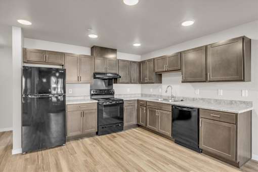 A modern kitchen with wooden floors and stainless steel appliances.