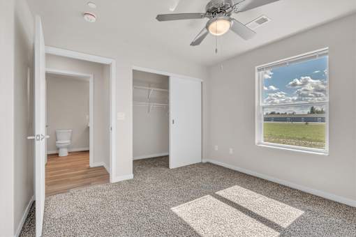 A room with a ceiling fan and a window showing the sky.