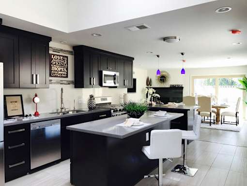 A modern kitchen with black cabinets and a white island.