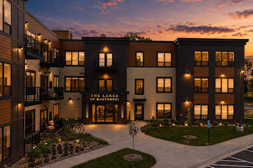 The image shows a modern apartment complex named "The Banks of Main Street" at dusk.