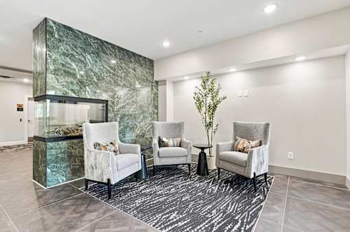 A living room with a green marble wall and white chairs.