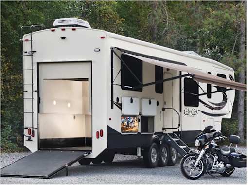A white RV is parked next to a black motorcycle.