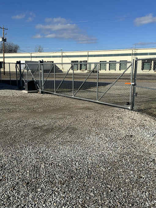 A metal gate blocks the entrance to a gravel lot.