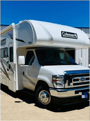 A Coleman camper is parked on a sunny day.