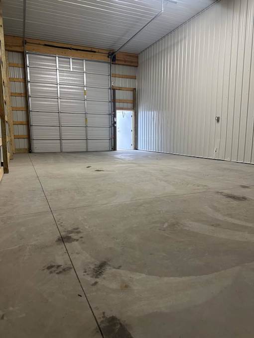 A large, empty warehouse with a closed metal door in the center.