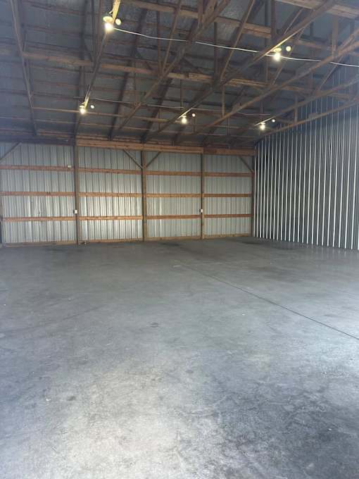 A large, empty warehouse with a concrete floor and a corrugated metal wall.