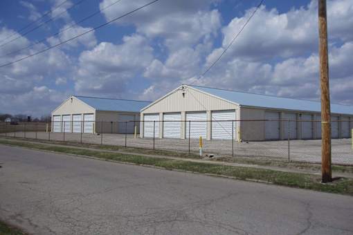 A large white building with a grey roof and a fence in front of it.