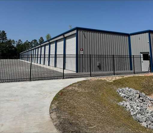 A large industrial building with a blue and white exterior and a black fence surrounding it.