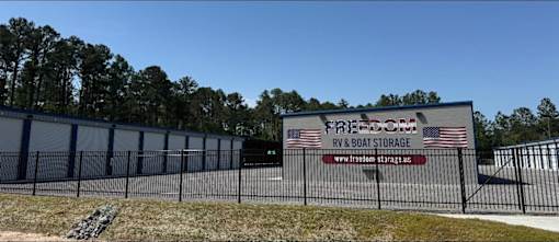 A fenced area with a sign that says Freedom RV & Boat Storage.
