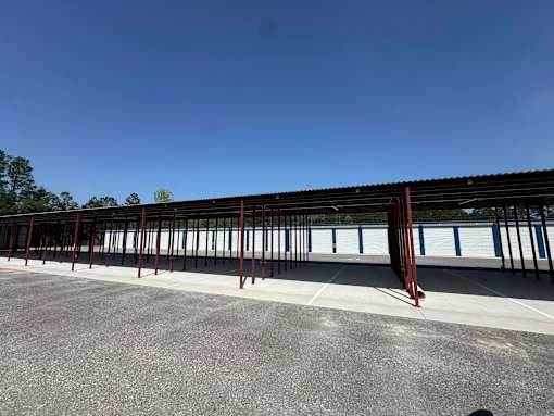 A parking lot with a long row of cars and a metal structure.