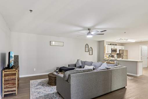 A living room with a grey couch and a ceiling fan.