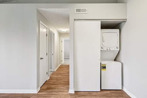 A white wall with a door and a fridge in the corner at Grand Valley Apartments, Milford, Ohio