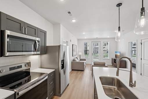A modern kitchen with stainless steel appliances and wooden floors.