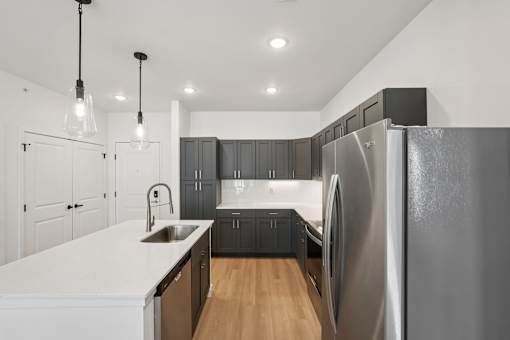 A modern kitchen with a large refrigerator and wooden floors.