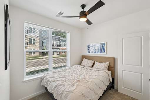 A bedroom with a large bed and a ceiling fan.