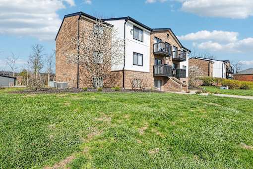 A large grassy area in front of a multi-story building at Grand Valley Apartments, OH, 46150