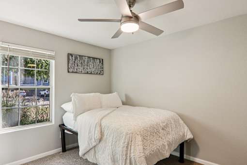 A bedroom with a bed, pillow, and a fan.