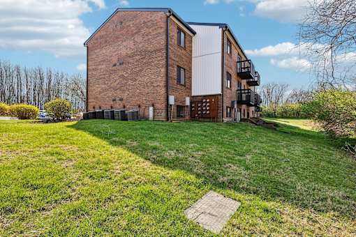 A large brick building with a white roof and a balcony on the second floor  at Grand  Valley Apartments, Milford, Ohio, 46150