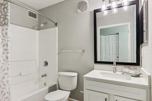 A white bathroom with a toilet, sink, and mirror.
