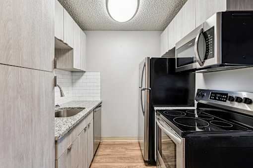 A kitchen with a blacke rfrigerator, stove, and microwave at Grand  Valley Apartments, Ohio, 46150