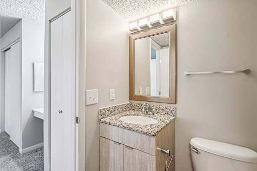 A bathroom with a sink, mirror, and toilet at The Reserve at Grand Valley Apartments, Milford 
