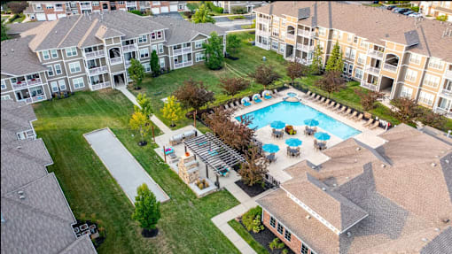 An aerial view of apartment buildings with a pool in the foreground.