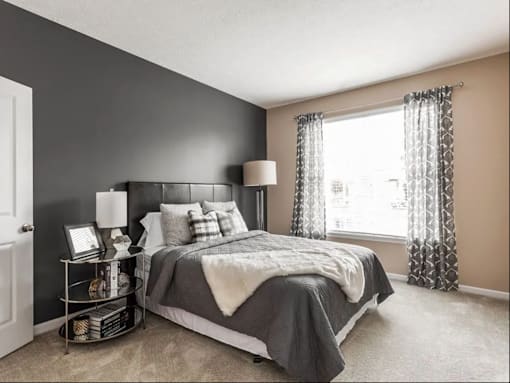 A bedroom with a bed, nightstand, and window.