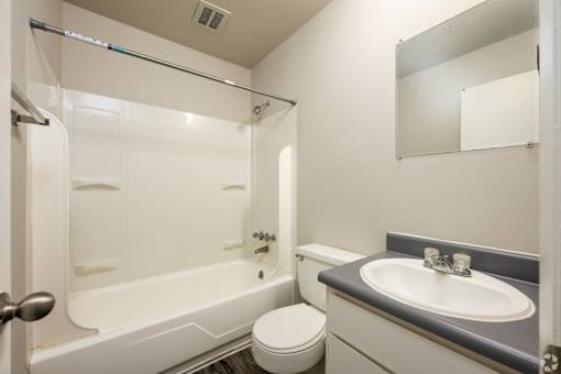 A white bathroom with a toilet, sink, and bathtub.