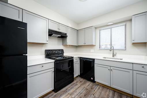 A kitchen with black appliances and white cabinets.