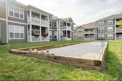 A backyard with a sandbox and apartment buildings in the background.