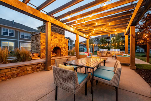 A patio with a table and chairs under a wooden pergola.
