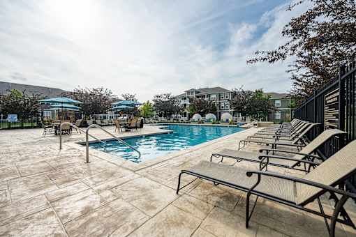 A pool surrounded by sun loungers and a building in the background.