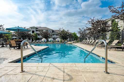 A swimming pool surrounded by lounge chairs and umbrellas.