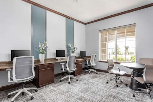 A room with a grey carpet and white chairs.