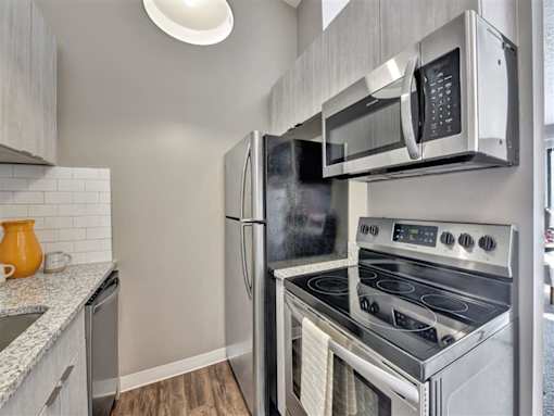 A modern kitchen with a stainless steel refrigerator, oven, and microwave at The Reserve at Grand Valley Apartments, Milford, OH